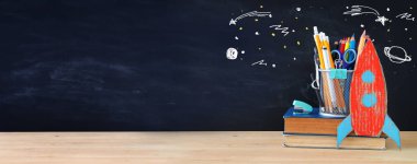 Geri okul kavramı. roket ve sınıf yazı tahtası önünde açık kitap üzerine kalem