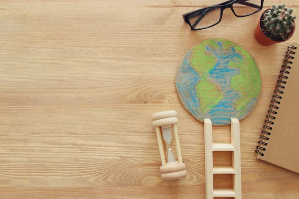 top view image of earth globe and ladder over wooden background.