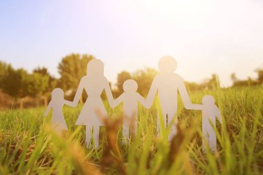 mutlu aile kavramı görüntüsü. Kağıt insanlar elele birlikte günbatımı sırasında yeşil çim kesme.