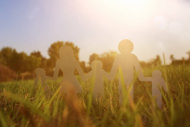 mutlu aile kavramı görüntüsü. Kağıt insanlar elele birlikte günbatımı sırasında yeşil çim kesme