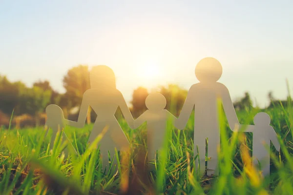 幸福家庭观念的形象 在日落时剪纸人牵手一起在绿草中 — 图库照片