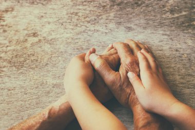 Yaşlı bir adam ve bir çocuğun el ele tutuşması.