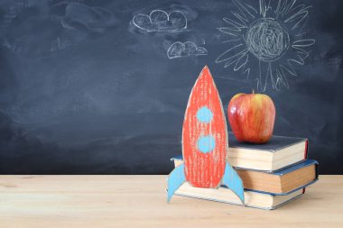 Geri okul afiş. Sınıf yazı tahtası önünde kitapların yanında karton roket boyalı