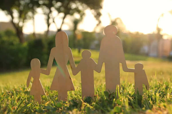 mutlu aile kavramı görüntüsü. ahşap kesim insanlar elele birlikte günbatımı sırasında yeşil çim