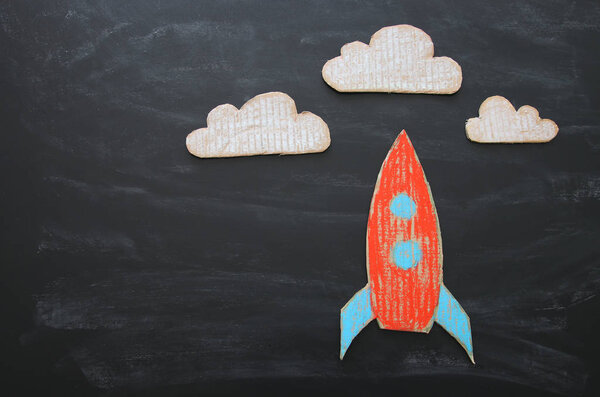 Rocket cut from cardboard and painted over chalkboard background