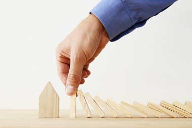Emlak sigorta ve koruma kavramı görüntüsü. adam ellerini domino etkisi, küçük bir ev kaydetmeden engelleme.