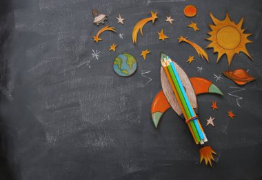 Geri okul kavramı. roket, kağıttan kesilmiş ve sınıf oda blackboard arka plan üzerinde boyalı alan öğeleri şekil
