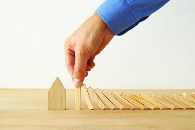 Emlak sigorta ve koruma kavramı görüntüsü. adam ellerini domino etkisi, küçük bir ev kaydetmeden engelleme