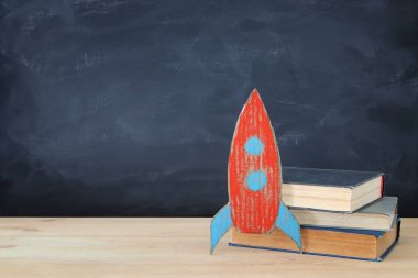 Geri okul afiş. Sınıf yazı tahtası önünde kitapların yanında karton roket boyalı