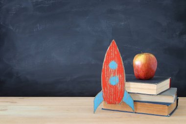Geri okul afiş. Sınıf yazı tahtası önünde kitapların yanında karton roket boyalı