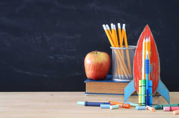 学校のコンセプトです 教室の黒板の前で本の段ボール ロケットと開いている鉛筆 — ストック写真