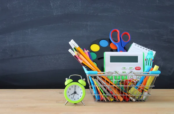 Carrinho de compras com material escolar em frente à lousa. Voltar ao conceito de escola . — Fotografia de Stock