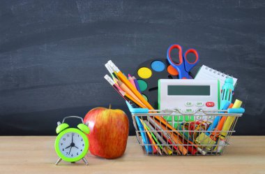 Alışveriş sepeti ile okul kaynağı yazı tahtası önünde. Geri okul kavramı