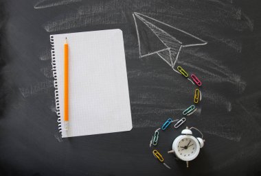 Üstten görünüm resmini uçak kroki yanındaki boş defter kağıt ve çalar saat sınıf tahta arka plan üzerinde