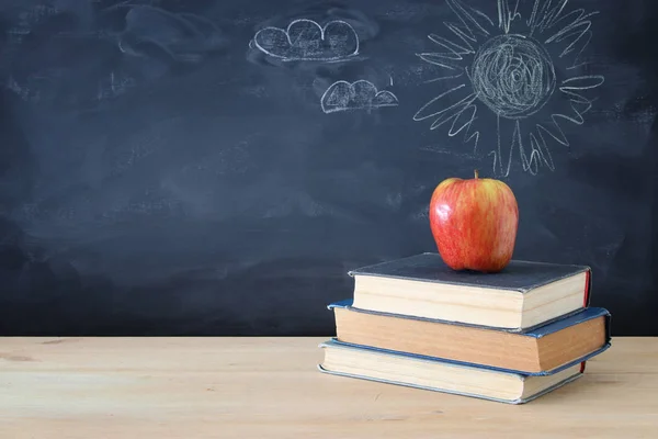 学校のコンセプトです 本と黒板の前に木製の机の上の Apple のスタック — ストック写真
