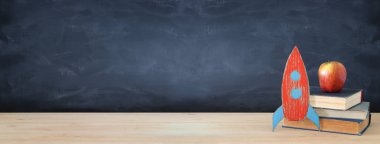 Geri okul afiş. Sınıf yazı tahtası önünde kitapların yanında karton roket boyalı