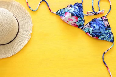 Moda bayan mayo bikini ve şapka sarı ahşap arka plan üzerinde düşük anahtar üstten görünüm. Yaz plaj tatil kavramı