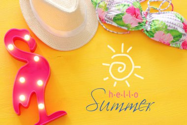 Üstten görünüm moda bayan mayo bikini ve beyaz fedora şapka sarı ahşap zemin üzerinde. Yaz plaj tatil kavramı