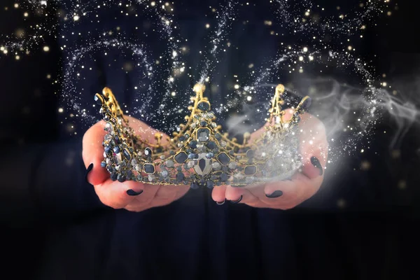 image of lady in black holding queen crown decorated with precious stones and magical glowing mysterious dust. fantasy medieval period. Black queen