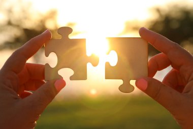 Bir kadın kavramı görüntüsünü bir bulmaca güneşin önünde iki adet tutan eller. Mercek parlaması ile günbatımı zamanı. yaratıcılık ve bağlantı fikir