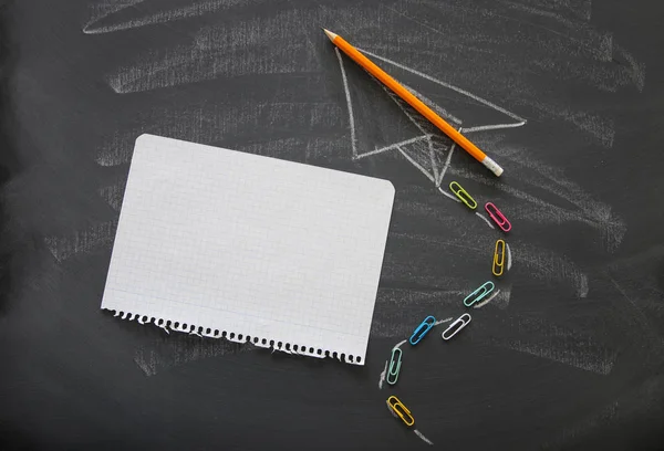 Top view image of plane sketch next to empty notebook paper over classroom blackboard background