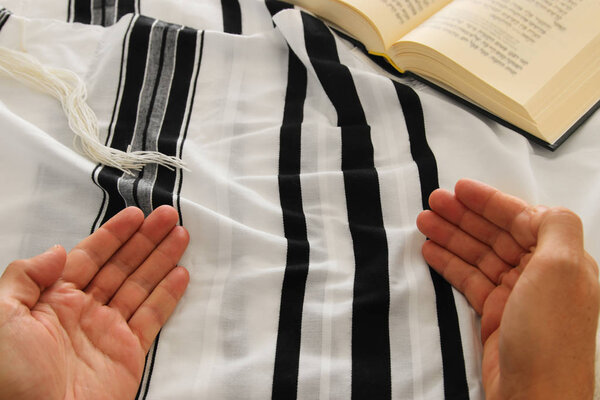 Jewish man hands next to Prayer book, praying, next to tallit. Jewish traditional symbols. Rosh hashanah (jewish New Year holiday), Shabbat and Yom kippur concept