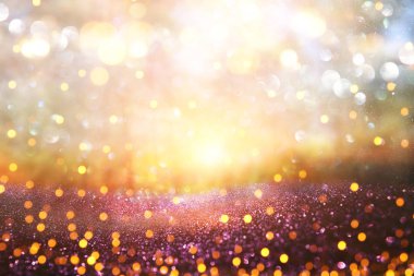 Ağaçlar arasında ışık patlaması ve parlak altın bokeh ışıklarının bulanık fotoğrafı.