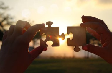 Bir kadın kavramı görüntüsünü bir bulmaca güneşin önünde iki adet tutan eller. Mercek parlaması ile günbatımı zamanı. yaratıcılık ve bağlantı fikir