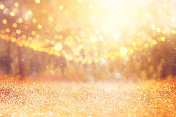 blurred abstract photo of light burst among trees and glitter golden bokeh lights