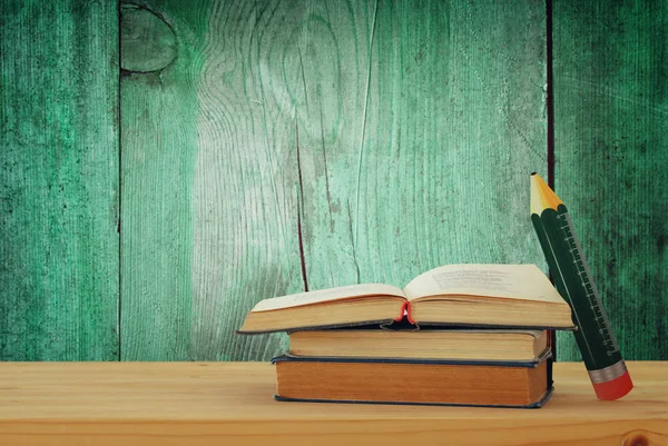 back to school concept. stack of books over wooden desk in front of wooden background