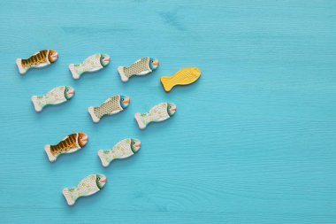 Ahşap arka plan üzerinde balık yüzme ile liderlik kavramı. Bir lider başkalarına yol açar