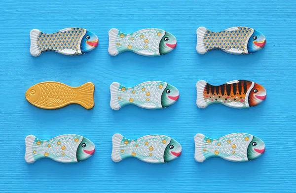 different fish swimming opposite way of identical ones. Courage and success concept