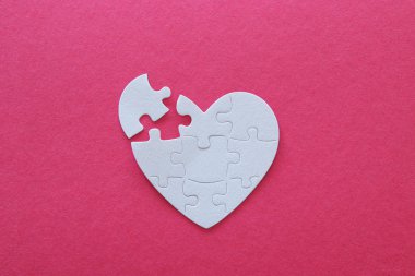 Üstten görünüm görüntü Kağıt beyaz kalp bulmacanın eksik parçası üzerinde pembe bir arka plan ile. Sağlık, bağış, Dünya Kalp günü ve Dünya Sağlık günü kavramı
