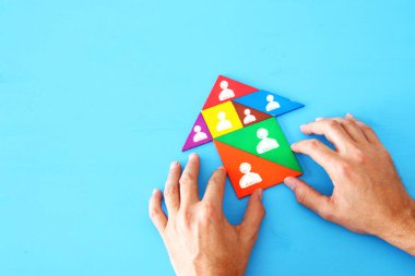 Ahşap masa, insan kaynakları ve yönetim kavramının üzerinde insanların simgeleri olan tangram bulmaca bloklarının görüntüsü