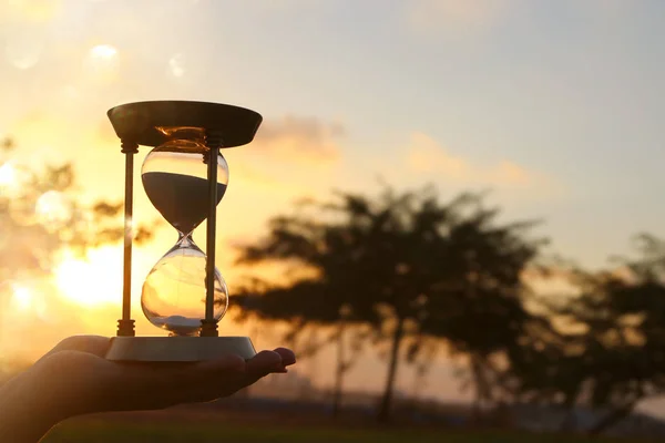 Молода жінка тримає Пісочний годинник під час заходу сонця. вінтажному стилі. — стокове фото