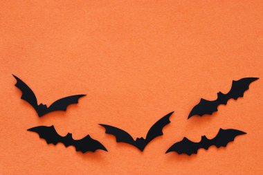 Cadılar Bayramı tatil kavramı. Turuncu arka plan üzerinde siyah yarasalar. Üstten görünüm, düz yatıyordu