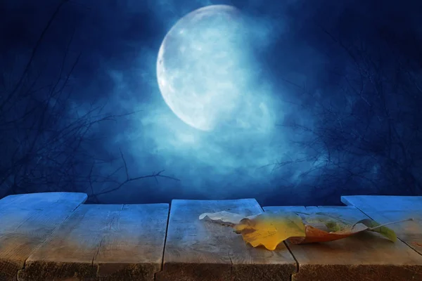 Concetto di festa di Halloween. Tavolo rustico vuoto di fronte al cielo notturno spaventoso e nebbioso con sfondo luna piena. Montaggio pronto per l'esposizione del prodotto . — Foto Stock