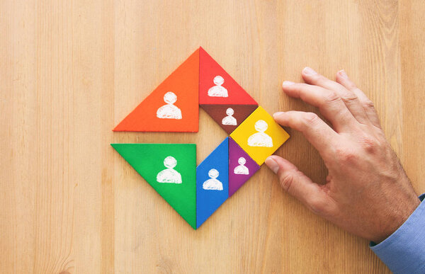 image of tangram puzzle blocks with people icons over wooden table ,human resources and management concept