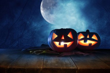 Cadılar Bayramı tatil kavramı. Gece korkunç, perili ve sisli orman, ahşap masa üzerinde boş rustik masa Pumpkins önünde. Ürün görüntü montaj için hazır