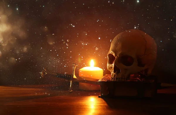 人間の頭蓋骨 古い本 古い木製のテーブルと暗い背景に非常に熱い蝋燭 — ストック写真