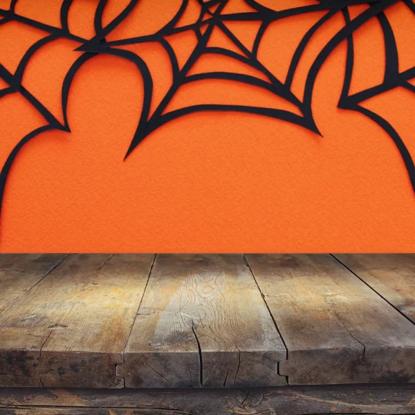 Halloween holiday concept. Empty rustic table in front of Spider webs over orange background. Ready for product display montage. Stock Photo