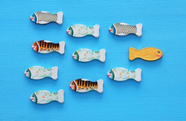 different fish swimming opposite way of identical ones. Courage and success concept clipart