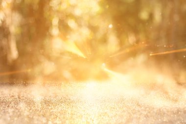 Ağaçlar arasında ışık patlaması ve parlak altın bokeh ışıklarının bulanık fotoğrafı.