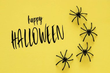 Cadılar Bayramı tatil kavramı. Sarı zemin üzerinde siyah örümcekler. Üstten görünüm, düz yatıyordu