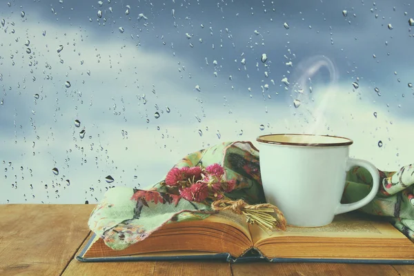 coffee cup on a rainy day over wooden table and window with rain drops background