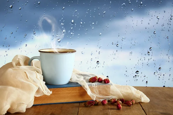 咖啡杯在雨天超过木桌和窗口与雨下落背景 — 图库照片
