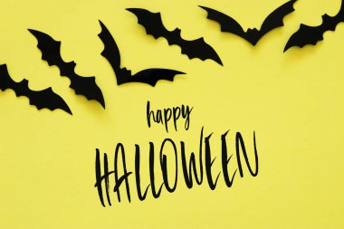 Cadılar Bayramı tatil kavramı. Sarı zemin üzerinde siyah yarasalar. Üstten görünüm, düz yatıyordu