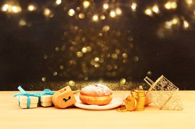 Image of jewish holiday Hanukkah with wooden dreidels (spinning top) and donut on the table clipart