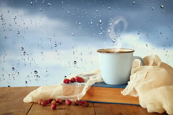 咖啡杯在雨天超过木桌和窗口与雨下落背景 — 图库照片