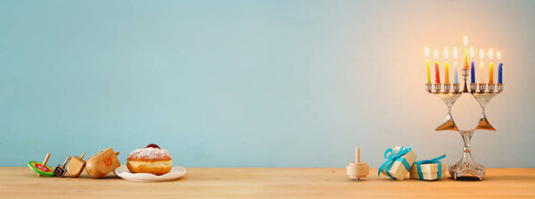 Banner of jewish holiday Hanukkah background with traditional spinnig top, menorah (traditional candelabra) and burning candles.